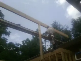 Carpenter setting a ridge beam over a new addition frame — Ice Dam Removal by Roofing Brothers in Newfane