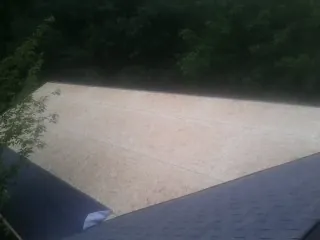 New OSB roof sheathing installed beside an existing shingle roof in Newfane