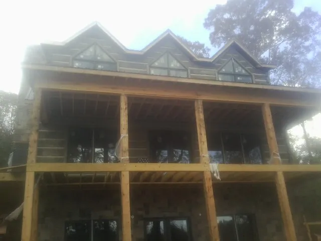 Dormers and porch framing on a large log home under construction — Roof Coating work by our crew in Newfane