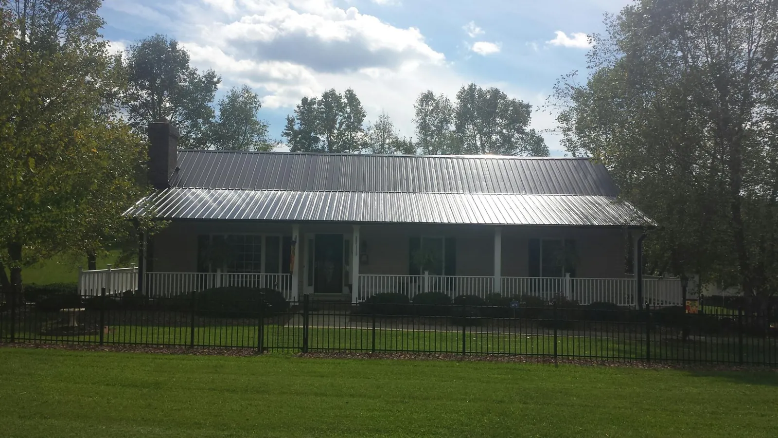 Gray metal roof on a brick ranch with a full width front porch — Gutter Guard Installation work by our crew in Newfane