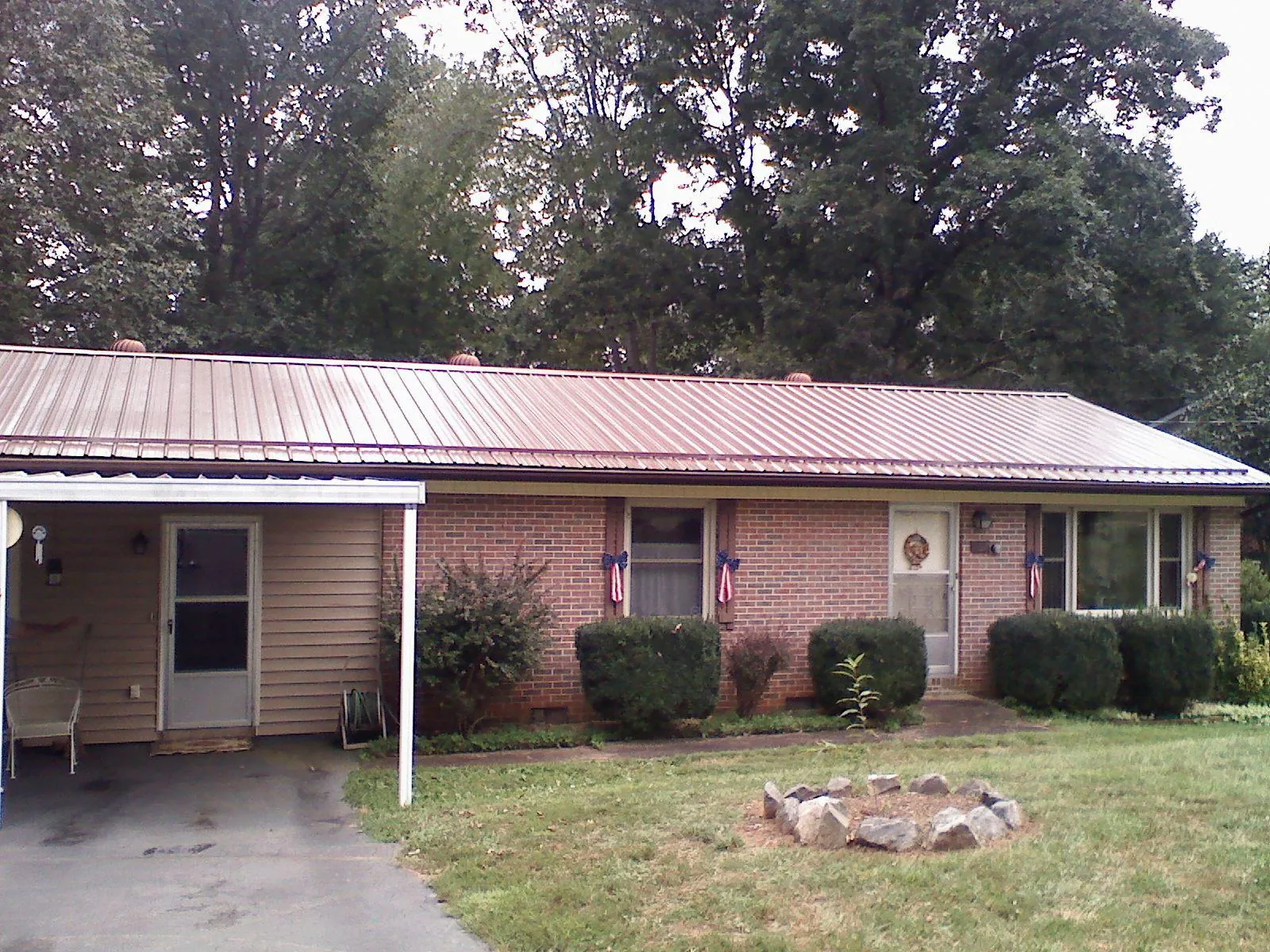 Bronze metal roof and carport on a brick ranch home — Roof Repair work by our crew in Newfane