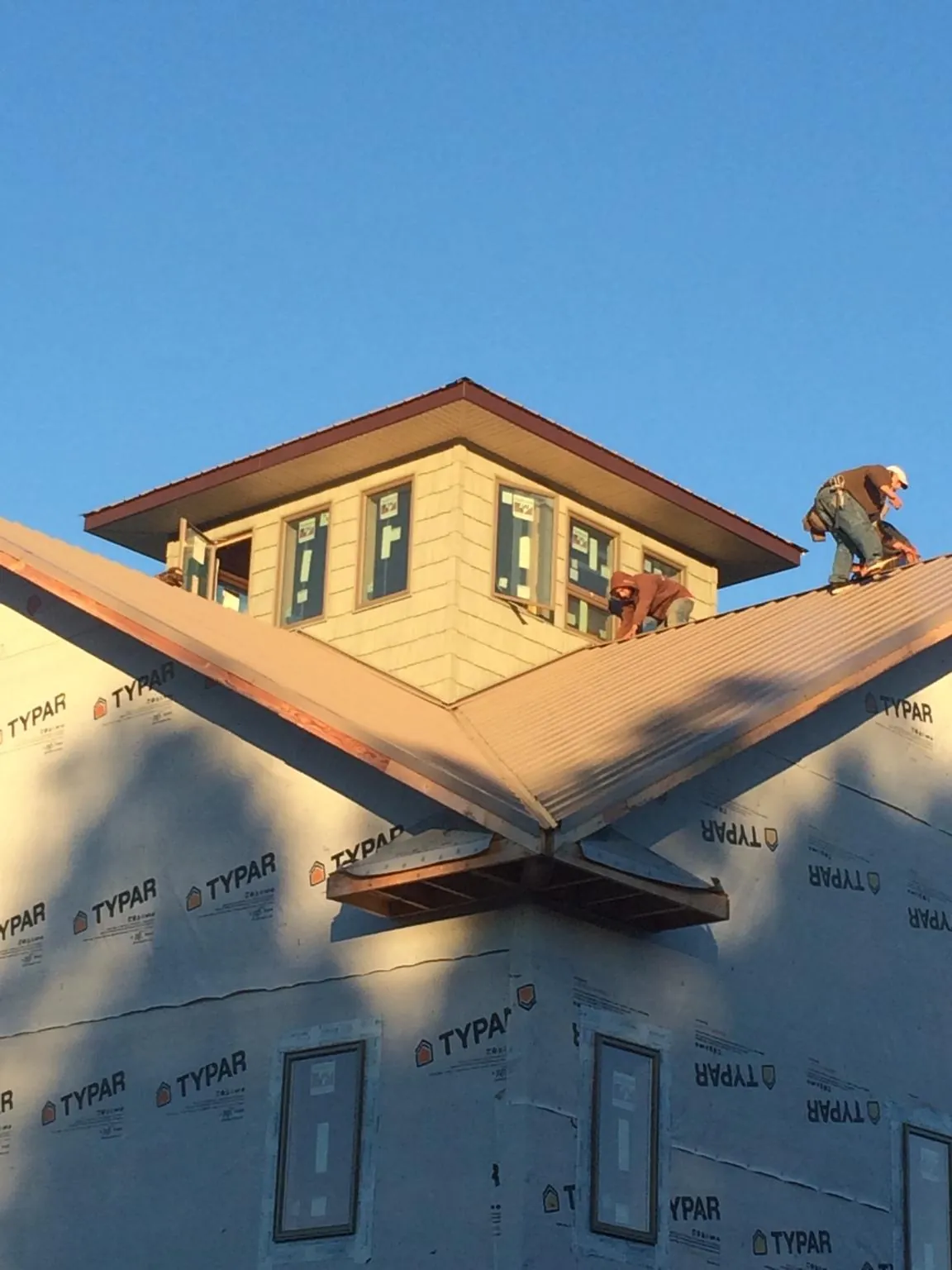Roofers working around a rooftop cupola on a new metal roof at sunset — Roof Waterproofing in Newfane by Roofing Brothers